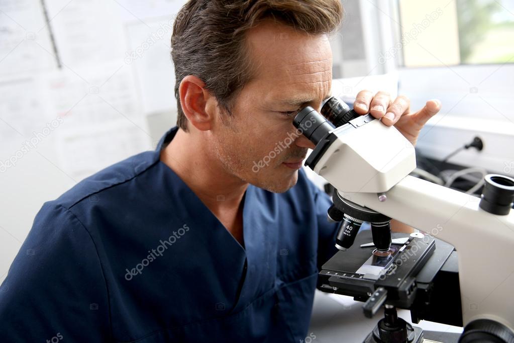 Doctor looking through microscope