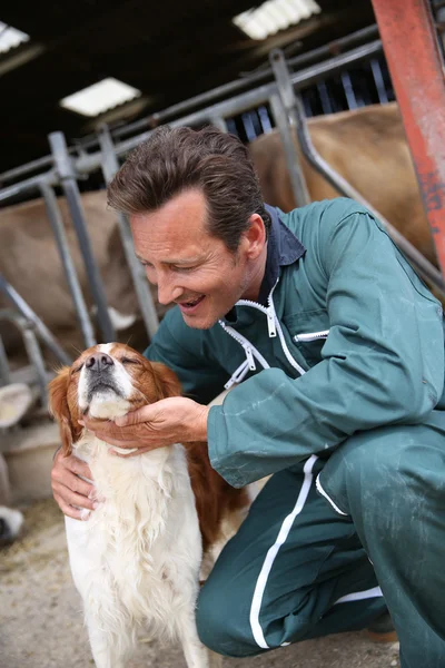 Criador acariciando perro fuera granero —  Fotos de Stock