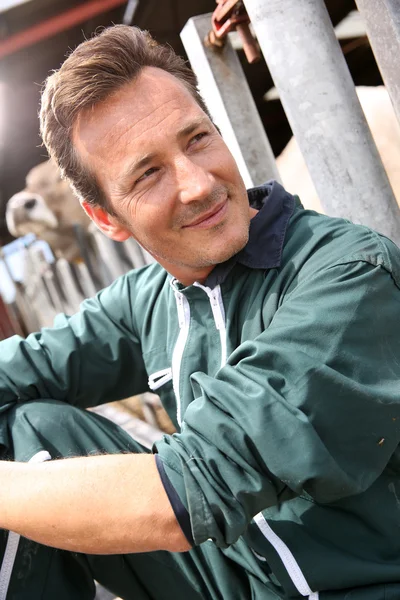 Smiling farmer sitting by barn — Stock Photo, Image