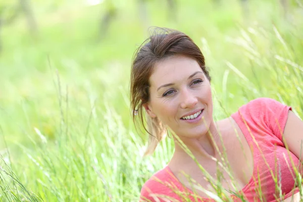 Lächelnde Frau liegt auf dem Feld — Stockfoto