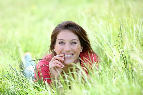 Lachende vrouw leggen in veld land — Stockfoto