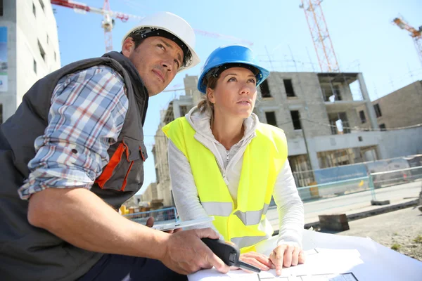 Ingenieure auf der Baustelle prüfen Pläne — Stockfoto