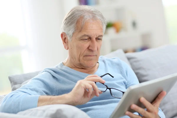 Старший читает новости на планшете — стоковое фото