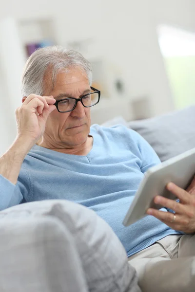 Homem sênior lendo notícias no tablet — Fotografia de Stock