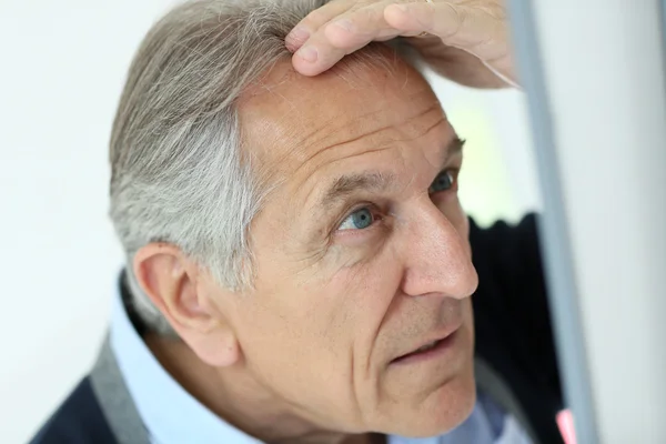 Hombre mirando la pérdida de cabello en el espejo —  Fotos de Stock