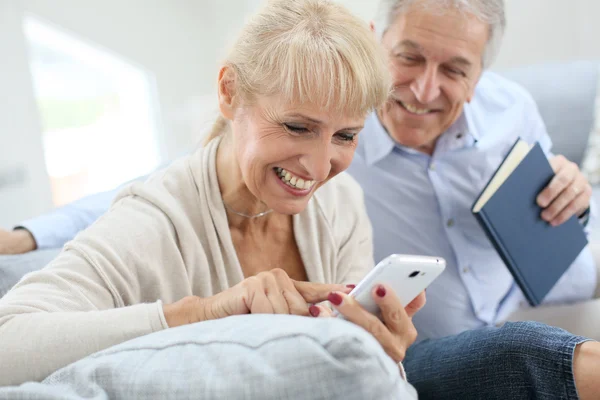 Kobieta za pomocą smartphone, mąż czytanie książki — Zdjęcie stockowe