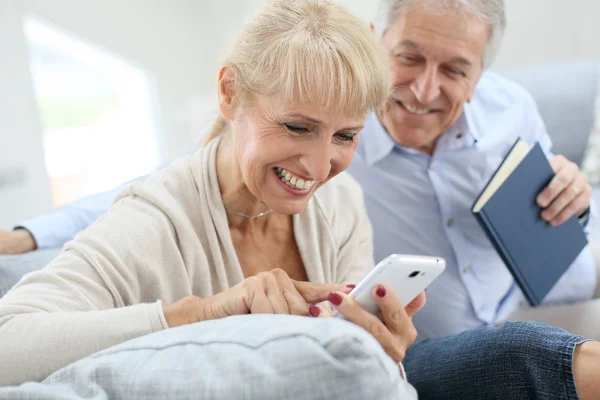 Kvinna med smartphone, man läser bok — Stockfoto