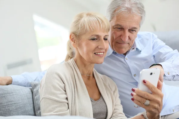 Pareja en casa usando smartphone — Foto de Stock