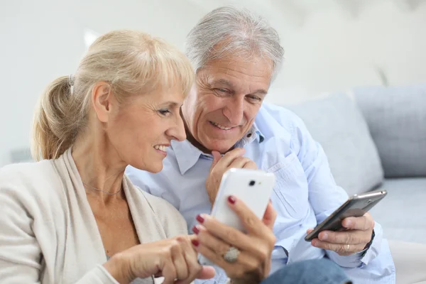 Casal em casa usando smartphone — Fotografia de Stock