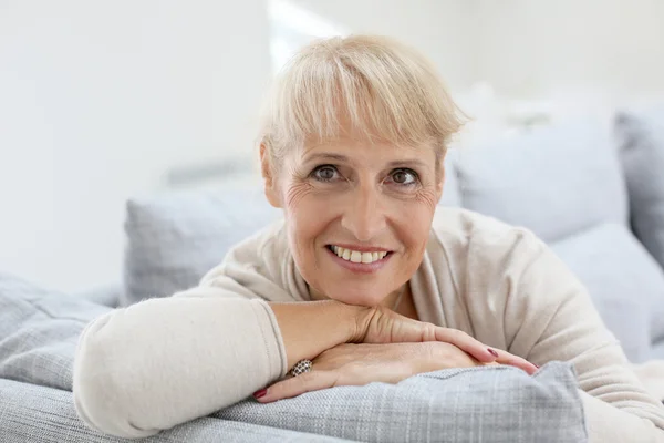 Lachende senior vrouw ontspannen op de sofa — Stockfoto