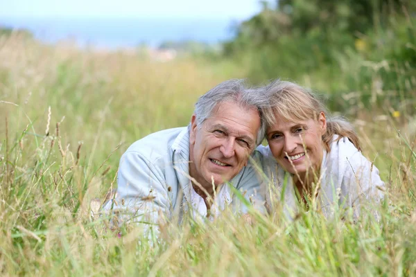 Paar legt sich auf Feld — Stockfoto