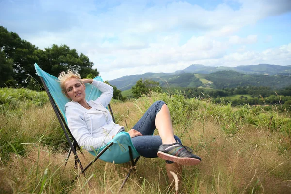 Mujer relajante en silla en el campo — Foto de Stock