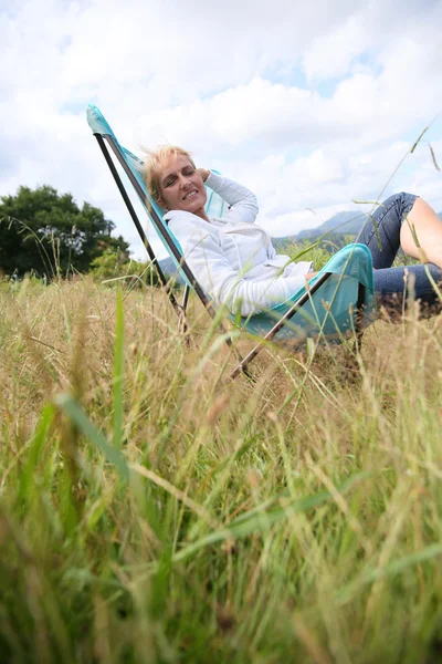 Mujer relajante en silla en el campo —  Fotos de Stock
