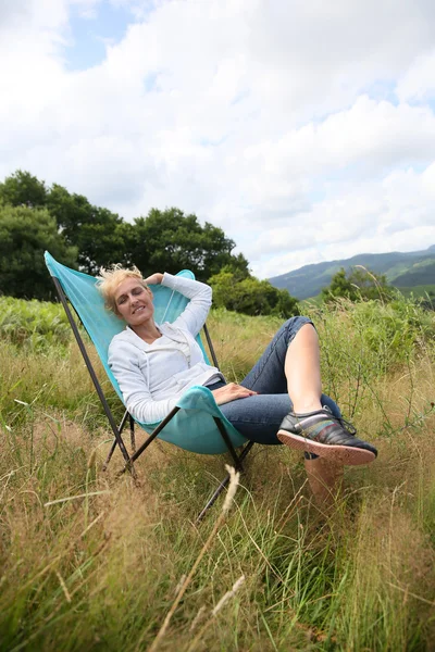 Mulher relaxante na cadeira no campo — Fotografia de Stock