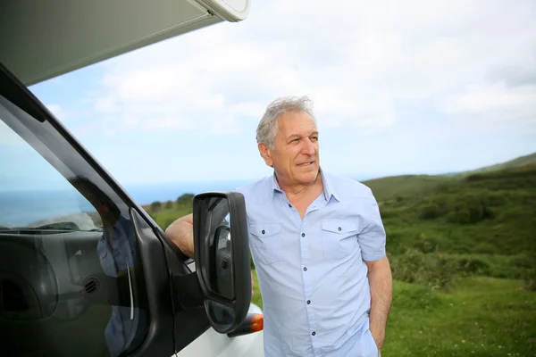 Senior man standing by camper — Stock Photo, Image