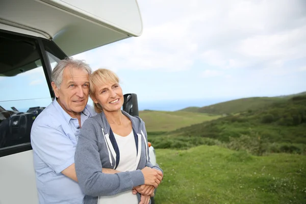 Casal em pé por motorhome no campo — Fotografia de Stock