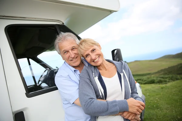 Casal em pé por motorhome no campo — Fotografia de Stock