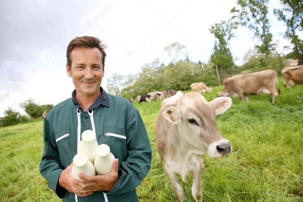 Farmer in field holding bottles of milk