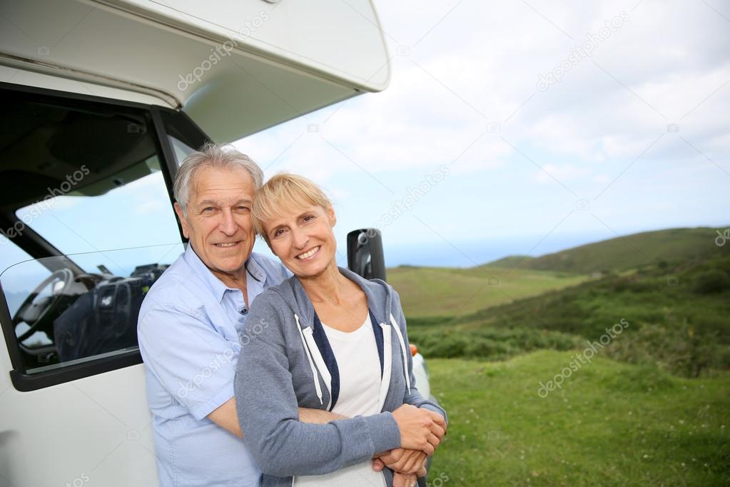 Couple standing by motorhome in countryside