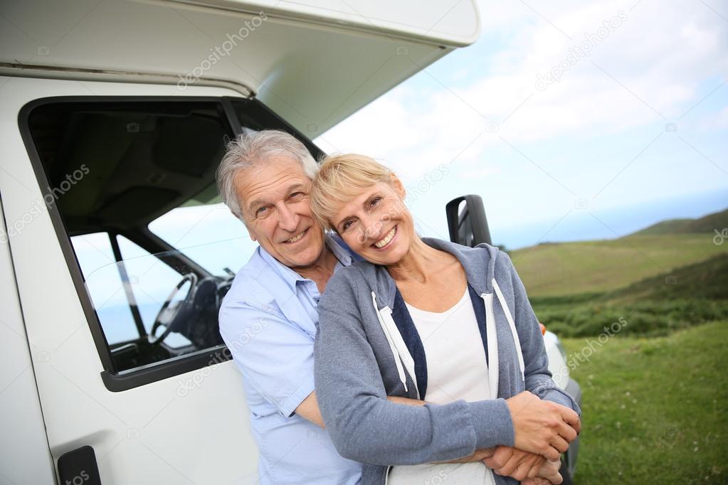 Couple standing by motorhome in countryside