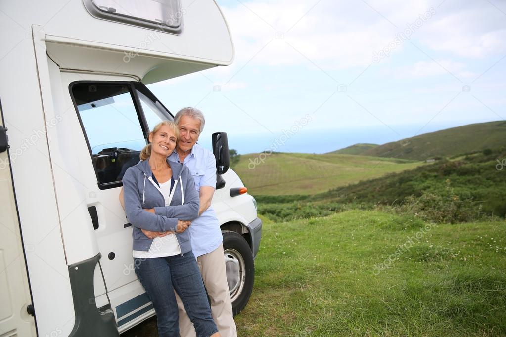 Couple standing by motorhome in countryside
