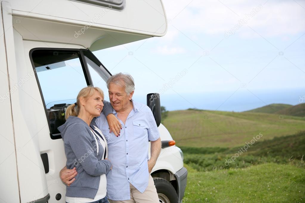 Couple standing by motorhome in countryside