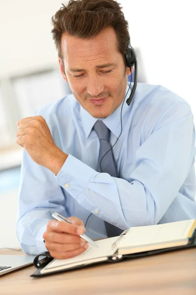 Empresário falando ao telefone com fone de ouvido — Fotografia de Stock