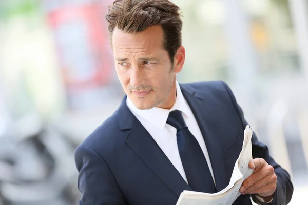 Businessman in town holding newspaper — Stock Photo, Image