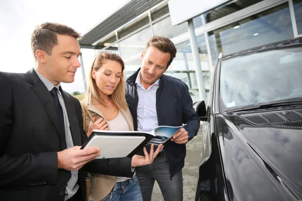 Car dealer showing vehicles to couple — Stock Photo, Image