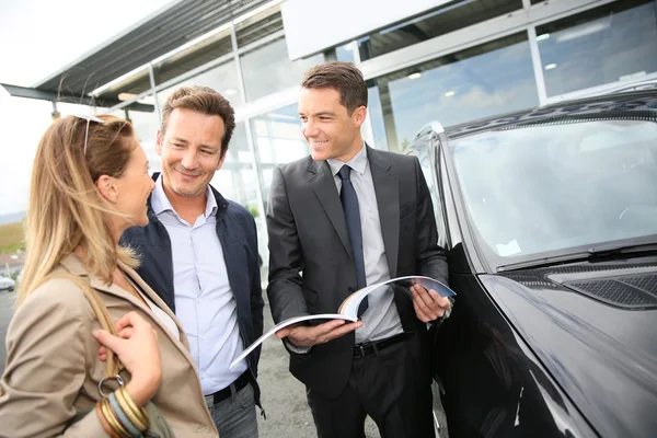 Car dealer showing vehicles to couple — Stock Photo, Image