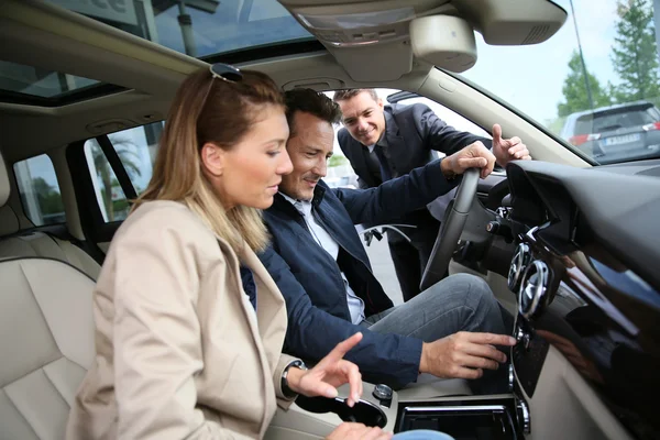 Car dealer showing vehicle to clients — Stock Photo, Image