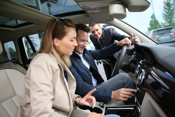 Car dealer showing vehicle to clients