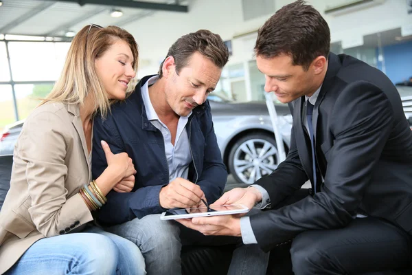 Couple signing car purchase order — Stock Photo, Image