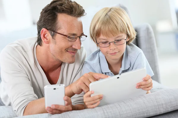 Far och son med tablett och smartphone — Stockfoto