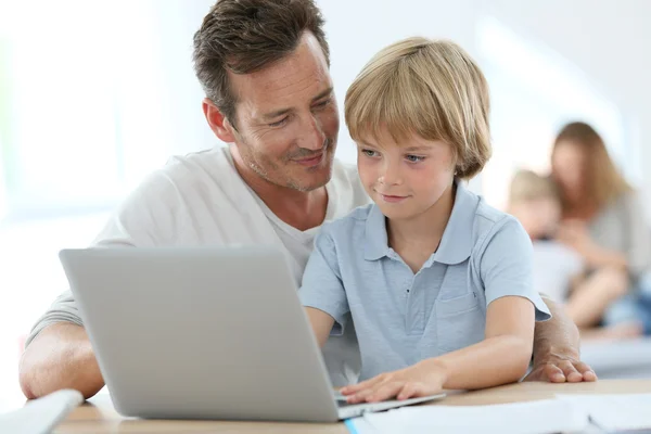 Человек с маленьким мальчиком играет на ноутбуке — стоковое фото