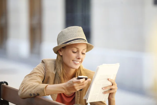 Frau liest Zeitung auf öffentlicher Bank — Stockfoto