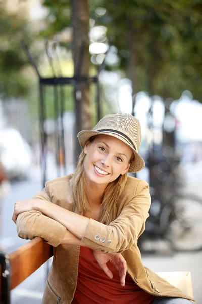 Femme souriante assise sur un banc public — Photo