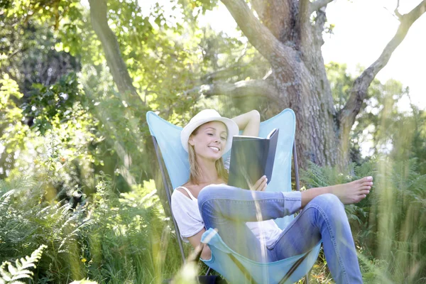 Woman reading book in outdoor chair — Stock Photo, Image