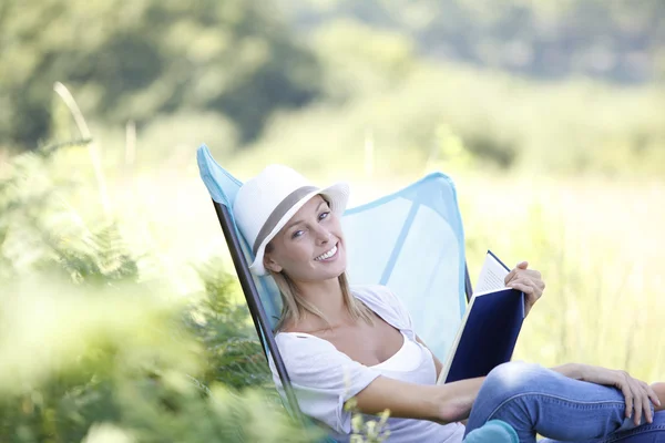 Woman reading book in outdoor chair — Stock Photo, Image