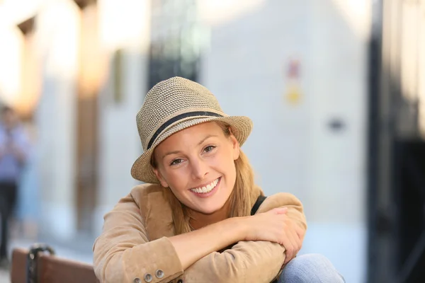 Flicka med hatt som sitter på bänken — Stockfoto