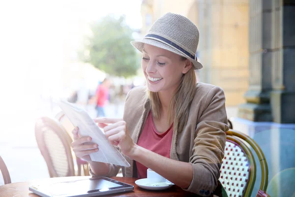 Dziewczyna w kawiarni czytanie gazety — Zdjęcie stockowe