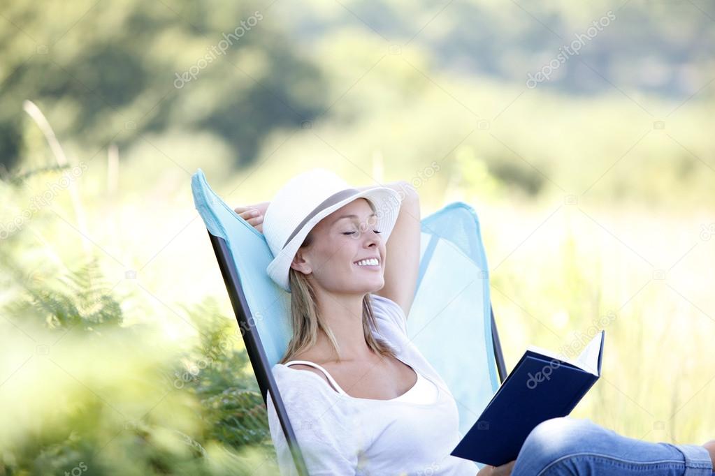 Woman reading book in outdoor chair