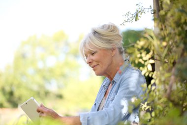 Üst düzey kadın bahçede tablet kullanma