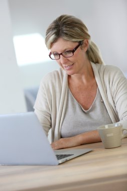 Evde dizüstü bilgisayarda çalışan bir kadın.