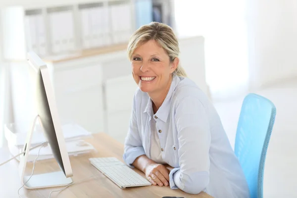 Geschäftsfrau sitzt vor Schreibtisch — Stockfoto