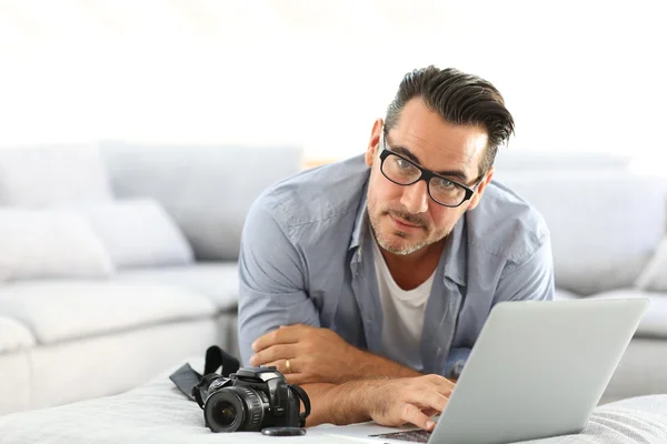 Homme utilisant un appareil photo reflex et un ordinateur portable — Photo