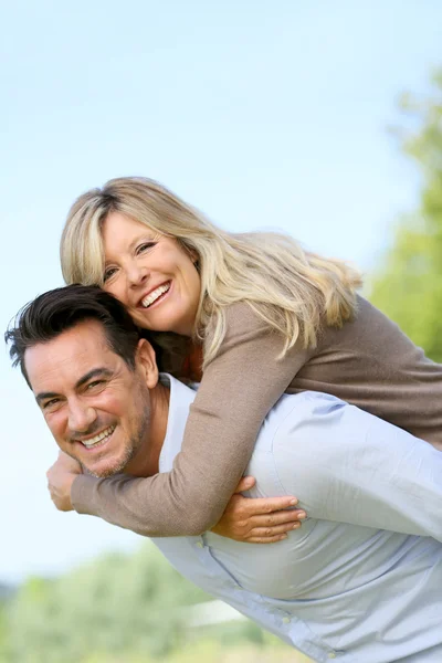 Homem dando piggyback passeio para mulher — Fotografia de Stock