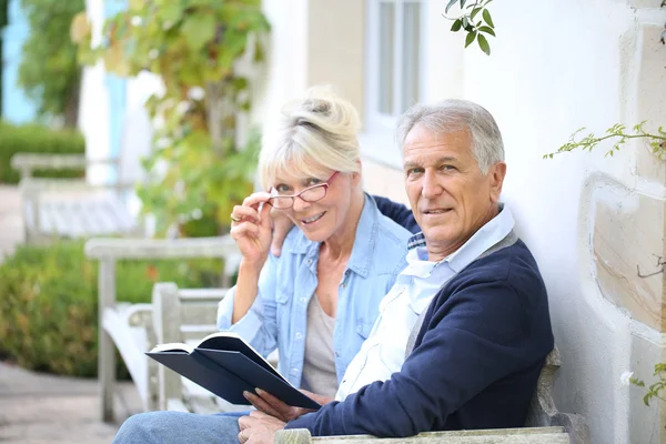 Seniorenpaar liest draußen Buch — Stockfoto