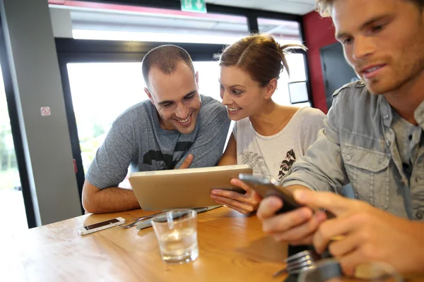 Students in campus lounge websurfing on tablet — Stock Photo, Image