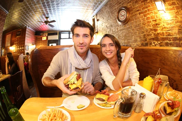 Pareja comiendo hamburguesa en restaurante — Foto de Stock